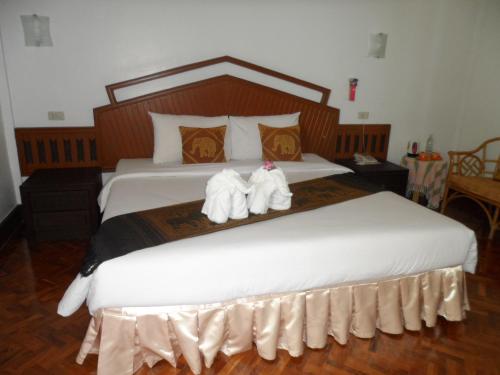 a bedroom with a large white bed with towels on it at Baiyoke Chalet Hotel in Mae Hong Son