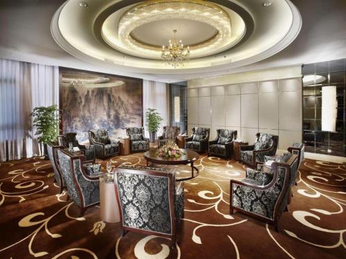 a lobby with chairs and a table and a chandelier at Royal Tulip Hotel Zhujiajiao Shanghai in Shanghai