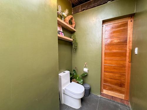 a bathroom with a toilet and a wooden door at Kismet House Central & Private Cozy Home in General Luna in General Luna