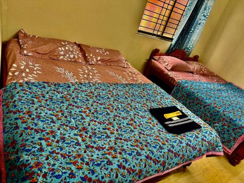 a bed with a comforter with a book on it at Anna Miracle Homestay in Kāsarkod