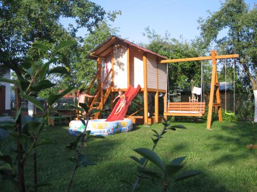 een klein huis met een speeltuin in de tuin bij Pokoje i domki nad Kanałem Bystrym in Augustów