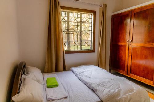 een slaapkamer met een bed, een ladekast en een raam bij Arusha backpackers homes in Arusha
