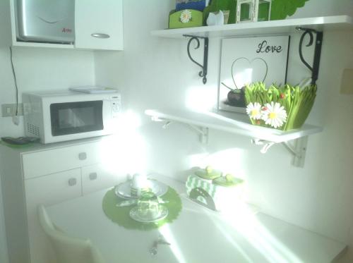a kitchen with a microwave and a table with flowers at B&B By Lussy - Camera Verde in Menaggio