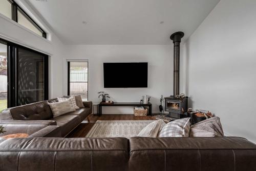 a living room with a couch and a flat screen tv at Luxury On Lakeside in Mount Beauty