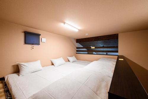 a bedroom with two white beds and a television at Hana-No-Mizuumi Hotel in Hakone