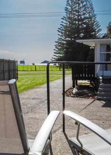 a porch with a chair and a bench and grass at Waitangi Beach Unit B in Paihia