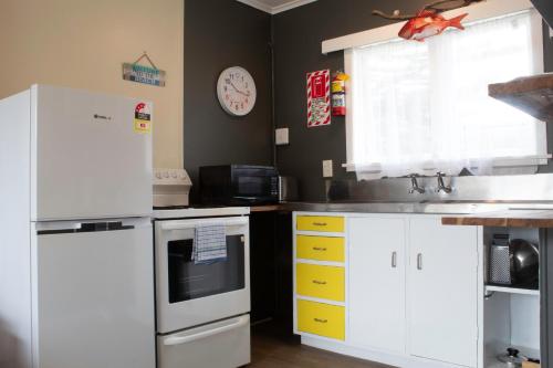a kitchen with white cabinets and a sink at Waitangi Beach Unit B in Paihia