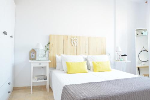 a white bedroom with a bed with yellow pillows at Aloja Dreams in Roquetas de Mar