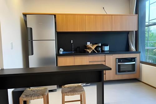 a kitchen with a refrigerator and a counter with stools at Beira mar porto de pedras essence C101 in Pôrto de Pedras