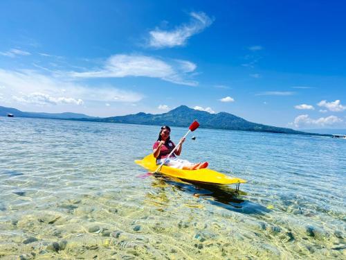 a woman sitting on a yellow kayak in the water at Three Ken Homestay & Cafe in Manado