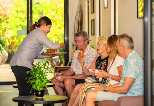 a woman holding a plate of food with a group of people at Angkor Land House in Phumĭ Réach Born