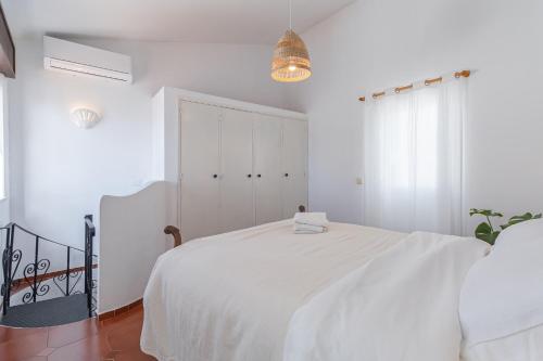 a white bedroom with a white bed and a window at Blue House Burgau in Burgau