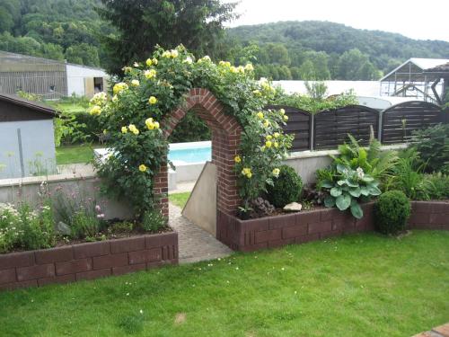 a garden with a brick arch with yellow flowers at Ferienwohnung Jena-Zoellnitz in Zöllnitz