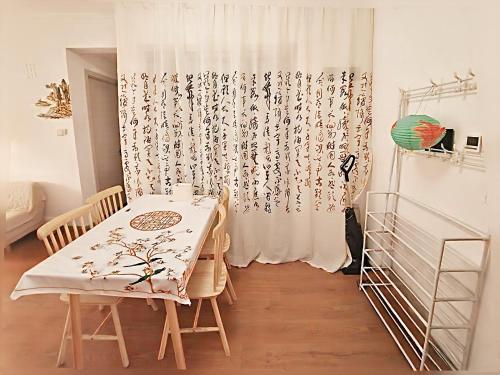 a dining room with a table and a curtain at Qingdao Linlin Tranquil Residence in Qingdao