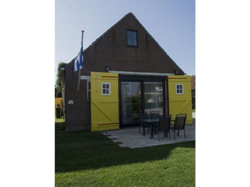a yellow house with a table and chairs at Holiday Home in Biggekerke near the Beach in Biggekerke