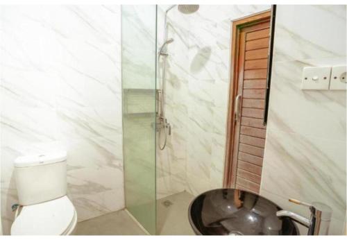 a bathroom with a toilet and a glass shower at Kubu D'Carik Villa & Bungalow by ecommerceloka in Munggu