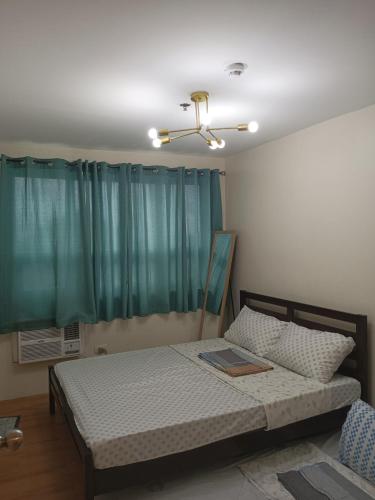 a bedroom with a bed with a green curtain at Seawind Condominium Near Airport in Davao City