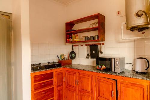 een keuken met houten kasten en een magnetron bij Arusha backpackers homes in Arusha