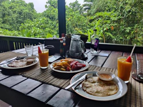 a wooden table with plates of food and drinks on it at Loh jinawi Guest House Bunaken in Bunaken