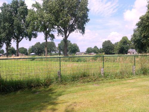 a fence in a field with trees in the background at Holiday home in with cycling area in Den Ham