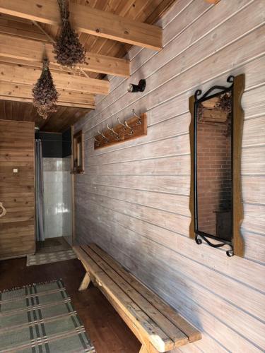 a room with a wooden wall with a bench and a mirror at Akmens sala in Vecpiebalga