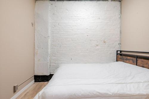 a bed in a room with a white brick wall at Great 1BR Apartment near VIA Rail in London