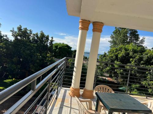 a porch with a table and chairs on a balcony at Hotel Royal Nest Entebbe in Entebbe