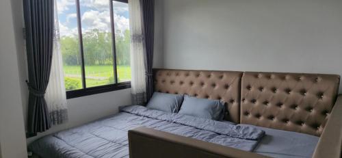 un lit dans une chambre avec une grande fenêtre dans l'établissement Harary Family apartments, à Amphoe Sawang Daen Din