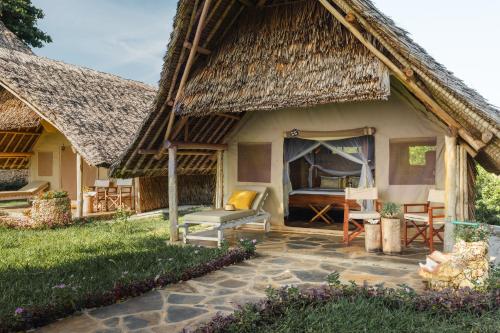 a house with a thatched roof and a patio at Mwazaro Beach Lodge in Shimoni