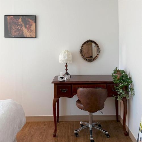 1 dormitorio con escritorio con silla y espejo en Magnolia Wonju branch, en Wonju