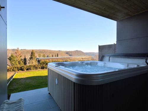a hot tub on a patio with a view of a yard at Luxurious Cottage in Aywaille with Sauna in Aywaille