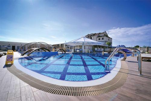 a large swimming pool with blue water in a building at Hotel Aria in Podgorica