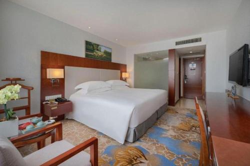 a bedroom with a large white bed and a television at Xiamen Airlines Quanzhou Hotel in Quanzhou