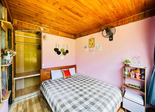 a small bedroom with a bed and wooden ceilings at Terrace House Tả Van in Sa Pa