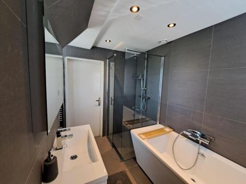 a bathroom with a sink and a tub and a shower at Ruime woning met jacuzzi, 10 min van strand in Lisse