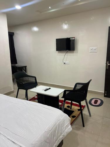 a room with a bed and two chairs and a tv at Hotel Abhimanyu Villa in Hyderabad