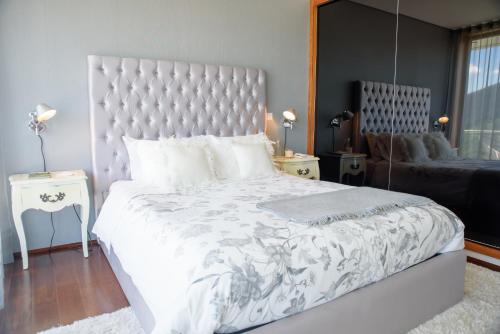 a bedroom with a large white bed with a large headboard at Quinta Do Bosque in Mesão Frio