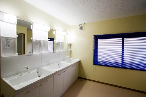 a bathroom with two sinks and two mirrors and a window at Guesthouse Fujinokura Kawaguchiko Ekimaeten in Fujikawaguchiko