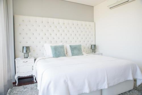 a white bedroom with a large white bed with blue pillows at Quinta Do Bosque in Mesão Frio