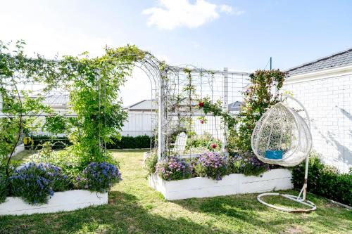 a garden with an arch with flowers and a fan at Spacious Hamptons-style home with plunge pool in Saint Leonards