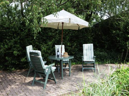 two chairs and a table with an umbrella at Farmhouse in Ulicoten near Forest Trails in Ulicoten