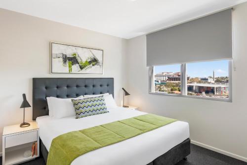 um quarto com uma cama grande e 2 janelas em Oaks Brisbane Woolloongabba Suites em Brisbane