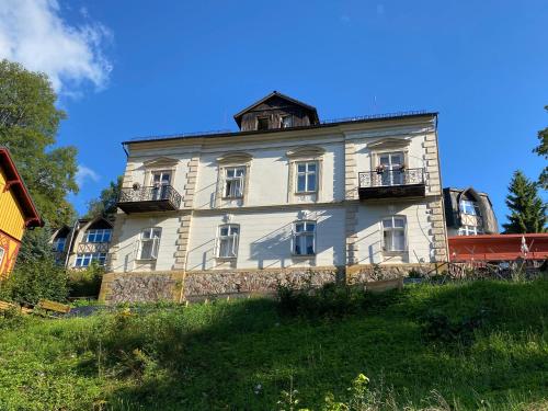 a large white building on top of a hill at Penzion Villa in Janske Lazne
