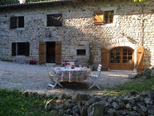 a table and chairs in front of a stone building at Secluded Stone Villa Retreat in Saint-Bonnet-le-Froid