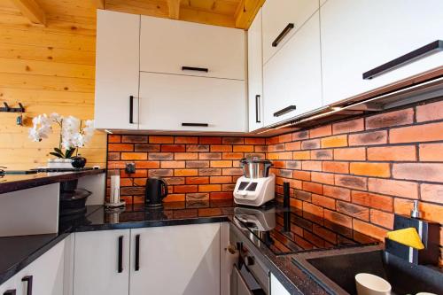 a kitchen with white cabinets and a brick wall at Ranczo pod laskiem 