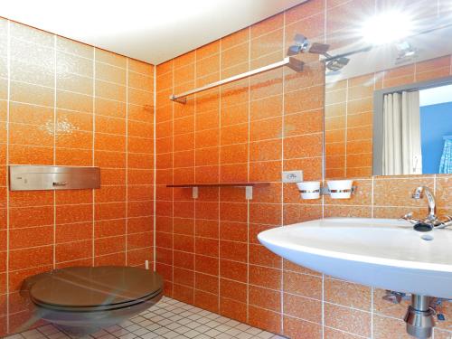 an orange tiled bathroom with a toilet and a sink at Pet-Friendly Escape in Fauvillers in Fauvillers