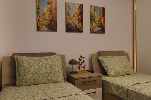 two beds in a room with paintings on the wall at Lilo HOME in Sibiu