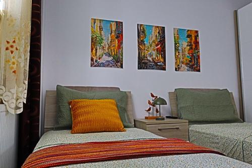 a bedroom with two beds and paintings on the wall at Lilo HOME in Sibiu