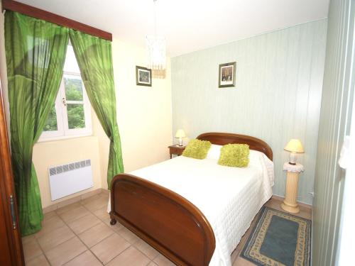 Un dormitorio con una cama con cortinas verdes y una ventana. en Cozy Family Home in Saint-Pons, en Berzème