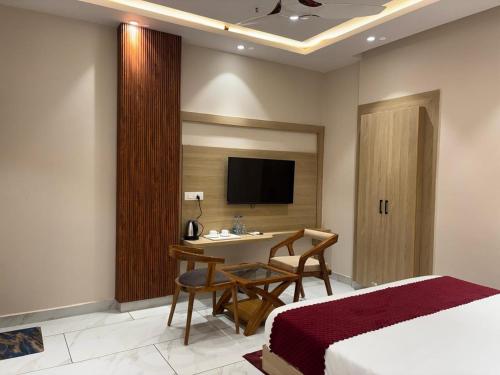 a bedroom with a bed and a desk and a tv at Mandonas Hotel and Resturant By StayApart in Siyāna